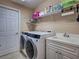 Well-lit laundry room features modern washer and dryer, utility sink, and storage shelves at 516 Tamiami S Trl # 303, Nokomis, FL 34275