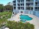 A serene pool area with a hot tub and patio furniture, set against the backdrop of a modern condominium building at 516 Tamiami S Trl # 303, Nokomis, FL 34275