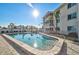 Community pool with sun-drenched deck, palm trees, and clear blue water at 708 Tamiami S Trl # 115, Venice, FL 34285