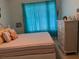 Bright bedroom with a striped bedspread and a window covered by blue curtains at 7201 L Pavia Blvd # 7201, Venice, FL 34292