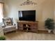 Cozy living room with patterned armchair, wood media cabinet, and neutral tones for a warm, inviting atmosphere at 7201 L Pavia Blvd # 7201, Venice, FL 34292