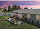 A dusk aerial view of backyard with patio, green lawn, and white vinyl fence at 7505 Wexford St, North Port, FL 34287
