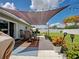 Outdoor patio with table and chairs, shade covering, and well manicured fenced lawn at 7505 Wexford St, North Port, FL 34287