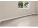 Bedroom with light beige walls, wood-look tile floor and view of trees through the window at 7582 Lyncrest St, North Port, FL 34287