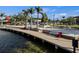 Water-level view of a pier and lakefront space with steps down to the water and red chairs to sit at 7582 Lyncrest St, North Port, FL 34287