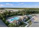 Aerial showcases a community pool, tennis courts, lake, and houses surrounded by green trees at 7582 Lyncrest St, North Port, FL 34287