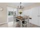 Bright dining area featuring a modern chandelier, seating for four, and access to the outdoors through sliding glass doors at 7582 Lyncrest St, North Port, FL 34287