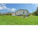 Backyard featuring a lush green lawn, well-maintained landscaping, and a home exterior at 763 Lakeside Dr, North Port, FL 34287
