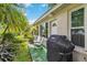 Relaxing back patio area with seating, a grill, and lush greenery, perfect for outdoor enjoyment at 1110 Southlake Ct, Venice, FL 34285