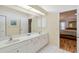 Bathroom with double sinks, white cabinetry, and a large mirror with great lighting at 1110 Southlake Ct, Venice, FL 34285