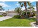 Inviting single-story home featuring a two-car garage and tropical landscaping with palm trees at 1110 Southlake Ct, Venice, FL 34285