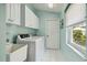 Bright laundry room features a washer, dryer, sink, and ample storage with white cabinets and a window at 1110 Southlake Ct, Venice, FL 34285