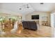 Open-concept living room with hardwood floors, a large TV, comfortable seating, and an adjacent dining area at 1110 Southlake Ct, Venice, FL 34285