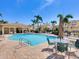 Resort-style community pool with tables, chairs, and sun umbrellas surrounded by lush tropical landscaping at 1164 Beachcomber Ct # 19, Osprey, FL 34229