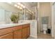 Bathroom with dual sinks, wood cabinets, glass enclosed shower, and a toilet at 11954 Tempest Harbor Loop, Venice, FL 34292