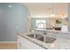 Kitchen sink with granite countertops and stainless steel faucet and view to the living space at 11954 Tempest Harbor Loop, Venice, FL 34292