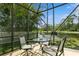 Screened in lanai with seating area overlooking a pond and lush green landscaping at 11954 Tempest Harbor Loop, Venice, FL 34292