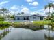 Waterfront home with lush landscaping, a serene lake, and views of the private pool with screened enclosure at 120 Hourglass Dr, Venice, FL 34293