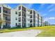 Modern condominium building with multiple screened balconies, surrounded by lush landscaping at 12140 Wellen Golf St # 202, Venice, FL 34293