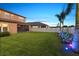 Fenced backyard with manicured lawn, swaying palm trees, and LED lighting illuminating the outdoor space at 12617 Oak Hill Way, Parrish, FL 34219