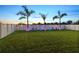 Backyard featuring manicured lawn, palm trees, patio chairs, and a white privacy fence with LED lighting at 12617 Oak Hill Way, Parrish, FL 34219