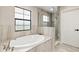 Bathroom showcasing a soaking tub with a tile surround and a glass-enclosed shower at 12617 Oak Hill Way, Parrish, FL 34219