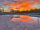 A resort-style pool with lounge chairs reflects a breathtaking sunset at 12617 Oak Hill Way, Parrish, FL 34219