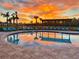 A tranquil pool reflects a vibrant sunset, creating a peaceful and inviting atmosphere at 12617 Oak Hill Way, Parrish, FL 34219