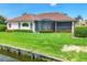 Home's backyard featuring a screened-in patio, lush green grass, and canal view at 1345 Reserve Dr, Venice, FL 34285
