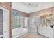 Bathroom featuring a soaking tub, glass block window, tiled shower, and large vanity at 1345 Reserve Dr, Venice, FL 34285