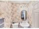 Quaint half bathroom featuring floral wallpaper, a white sink, mirror and toilet at 1345 Reserve Dr, Venice, FL 34285