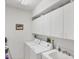 Bright laundry room with a sink, washer, dryer and plenty of white cabinets for storage at 1345 Reserve Dr, Venice, FL 34285