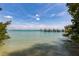 Scenic water view of a pier extending into clear turquoise water, framed by lush greenery at 137 Mariner Ln, Rotonda West, FL 33947