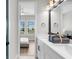 Bathroom featuring a double sink vanity, large mirror and a view to the main bedroom at 18136 Foxtail Loop, Venice, FL 34293