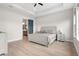 Bright bedroom features a tray ceiling, wood-look floors and an ensuite bath behind a blue door at 18136 Foxtail Loop, Venice, FL 34293