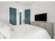 Stylish bedroom featuring a comfortable bed, a modern TV, and sleek teal doors at 18136 Foxtail Loop, Venice, FL 34293