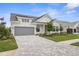 Charming two-story home with a gray garage door, complemented by stylish landscaping and a patterned driveway at 18136 Foxtail Loop, Venice, FL 34293