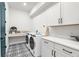 Clean laundry room featuring patterned tile, front load machines, and white cabinets for storage at 18136 Foxtail Loop, Venice, FL 34293