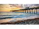 Scenic pier view extending into the ocean with people enjoying the sunset, embodying a tranquil coastal lifestyle at 18136 Foxtail Loop, Venice, FL 34293