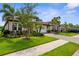 Beautifully landscaped front yard with lush green lawn, palm trees, and a paved driveway at 19927 Bridgetown Loop, Venice, FL 34293