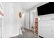 Hallway with gray carpeting leading to a bathroom and bedrooms, featuring a dresser and wall-mounted TV at 19927 Bridgetown Loop, Venice, FL 34293