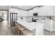 Bright kitchen features white cabinetry, stainless steel appliances, and a large center island with bar stool seating at 19927 Bridgetown Loop, Venice, FL 34293