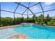 Lush landscaping surrounds a private pool and spa, enclosed by a screen for added privacy and comfort at 19927 Bridgetown Loop, Venice, FL 34293