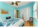 This bedroom with blue walls includes a large closet, plantation shutters, a ceiling fan, and wood flooring at 20169 Cristoforo Pl, Venice, FL 34293