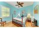 This bedroom with blue walls features a ceiling fan, a wooden bed frame, and plantation shutters for natural light at 20169 Cristoforo Pl, Venice, FL 34293