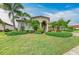 Beautifully landscaped front yard with lush green grass and tropical palm trees at 20169 Cristoforo Pl, Venice, FL 34293
