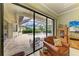 Bright living room featuring a leather chair and sliding glass doors to the screened pool area at 20169 Cristoforo Pl, Venice, FL 34293