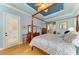 This main bedroom features hardwood floors, blue walls, a ceiling fan, and a four-poster bed with decorative pillows at 20169 Cristoforo Pl, Venice, FL 34293