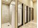A shower room with tiled walls, shower curtains, and multiple changing rooms at 20169 Cristoforo Pl, Venice, FL 34293