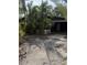 Exterior shot of a home with overgrown tropical foliage and gravel drive at 202 Bayview Pkwy, Nokomis, FL 34275
